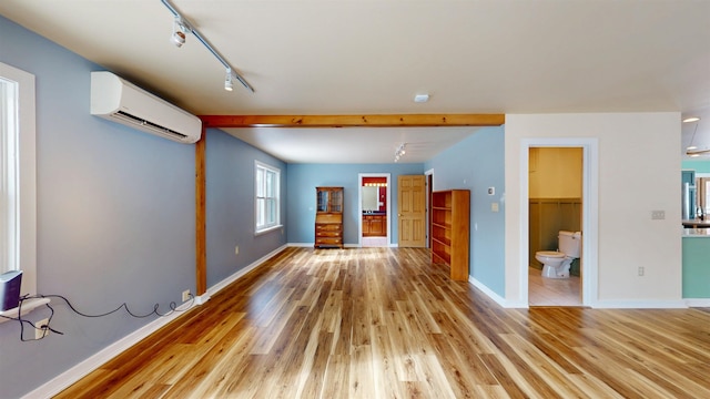 interior space featuring track lighting, a wall mounted AC, and light wood-type flooring