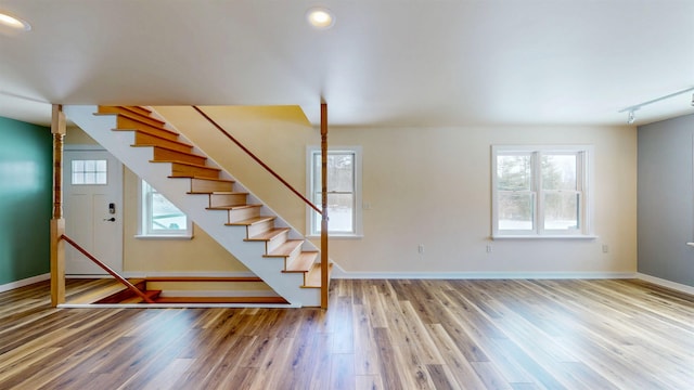 staircase with track lighting, wood-type flooring, and plenty of natural light