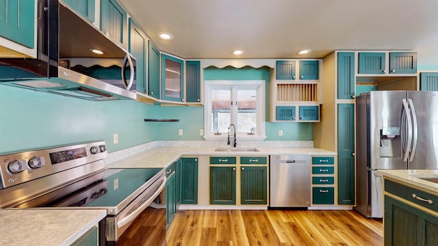 kitchen with stainless steel appliances, sink, light hardwood / wood-style floors, and green cabinetry