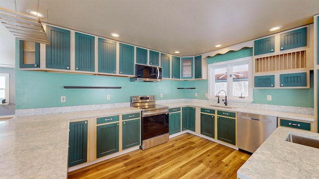 kitchen with sink, decorative light fixtures, light wood-type flooring, appliances with stainless steel finishes, and light stone countertops