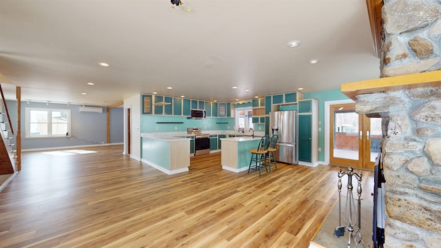 kitchen with a breakfast bar, a center island, light wood-type flooring, appliances with stainless steel finishes, and a wall unit AC