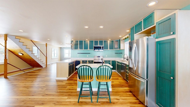 kitchen featuring a kitchen island, appliances with stainless steel finishes, a breakfast bar, sink, and light hardwood / wood-style flooring