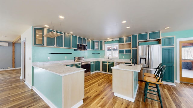 kitchen with stainless steel appliances, sink, a kitchen breakfast bar, and kitchen peninsula