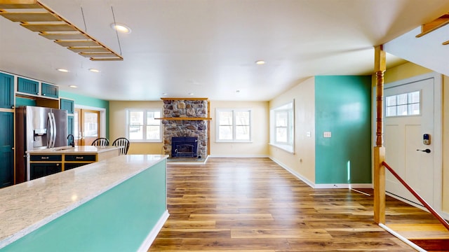 kitchen with hardwood / wood-style flooring, a fireplace, and stainless steel fridge with ice dispenser