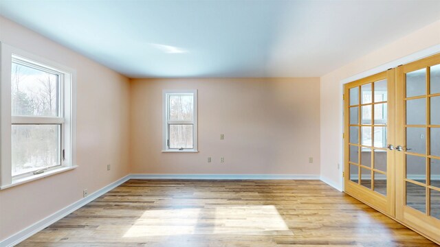 spare room with french doors and light hardwood / wood-style flooring