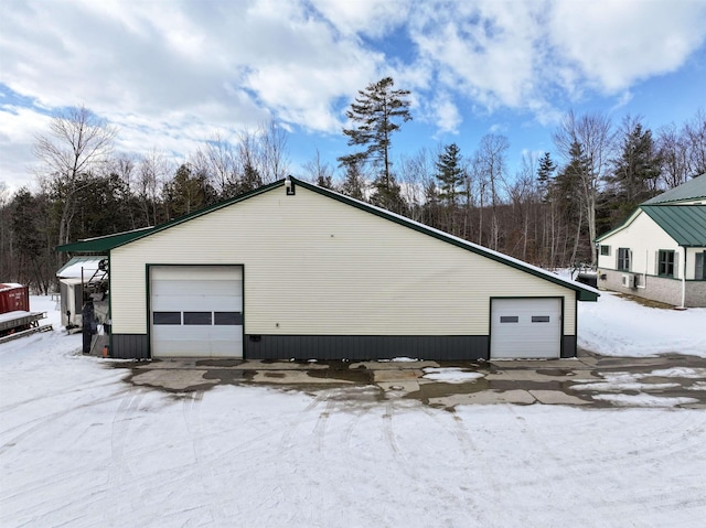 view of snow covered exterior with a garage and an outbuilding