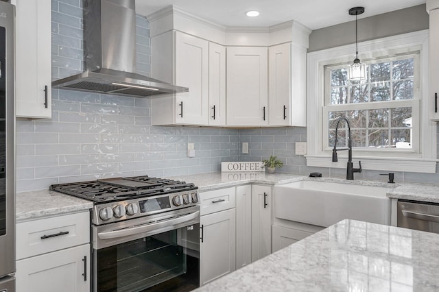 kitchen with wall chimney range hood, sink, appliances with stainless steel finishes, white cabinetry, and light stone countertops