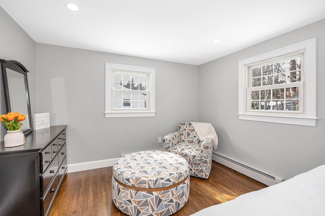 bedroom featuring baseboard heating, dark hardwood / wood-style flooring, and multiple windows