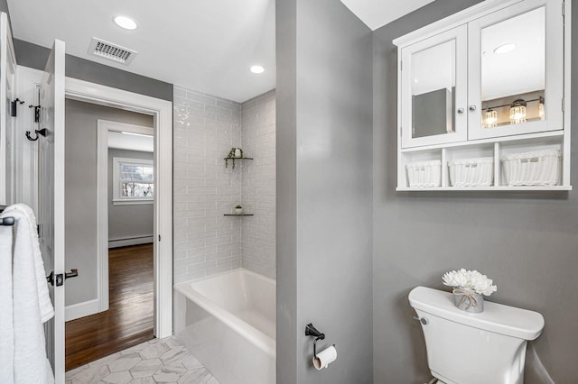 bathroom featuring tiled shower / bath combo, a baseboard radiator, and toilet