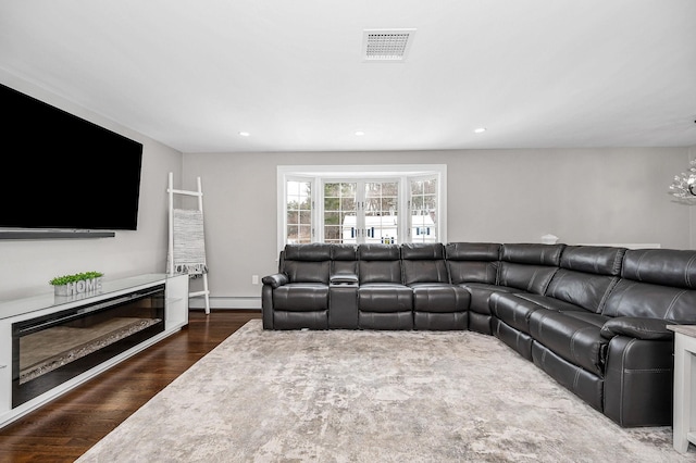 living room with a baseboard heating unit and dark hardwood / wood-style floors