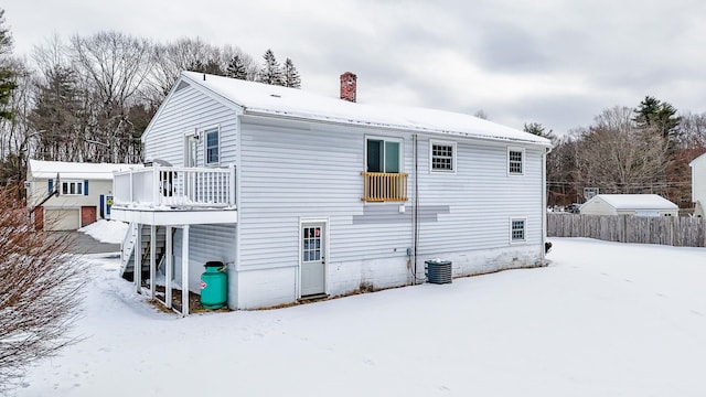 snow covered house with a wooden deck and central air condition unit