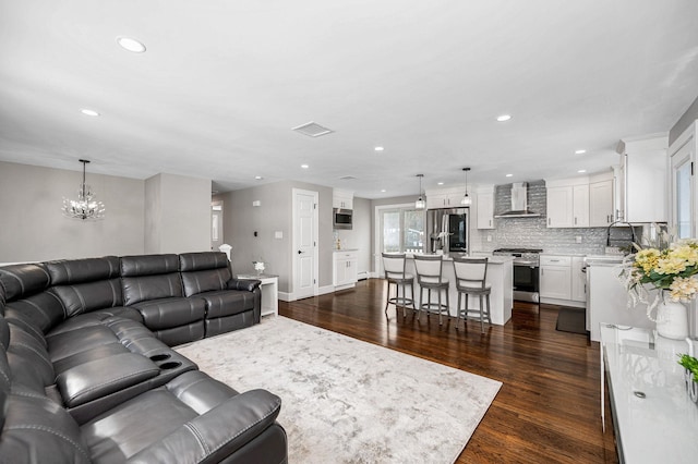 living room with an inviting chandelier, sink, and dark hardwood / wood-style floors