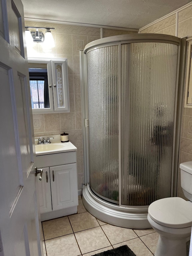 bathroom with a shower stall, vanity, tile walls, and tile patterned floors