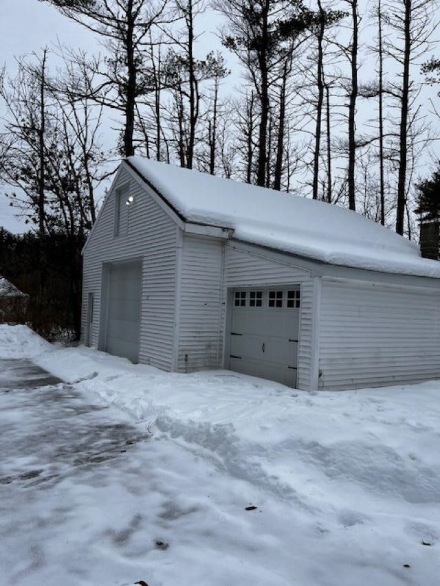 snow covered garage with a detached garage