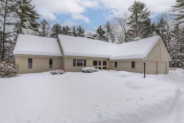 snow covered house featuring a garage