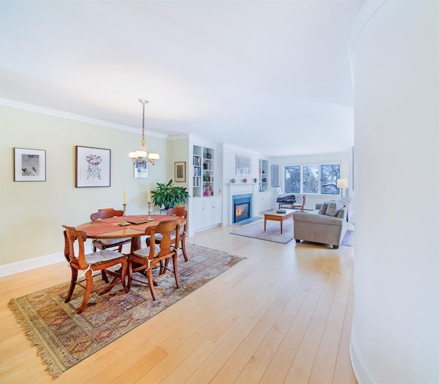 dining room featuring a notable chandelier, built in shelves, ornamental molding, and light hardwood / wood-style floors