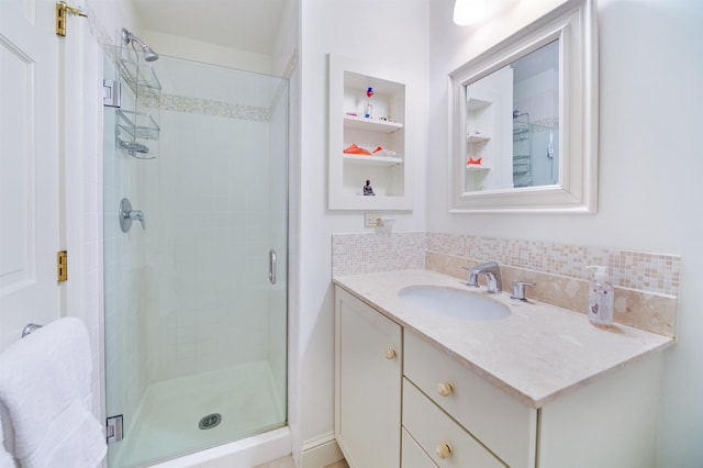 bathroom featuring an enclosed shower, vanity, and tasteful backsplash