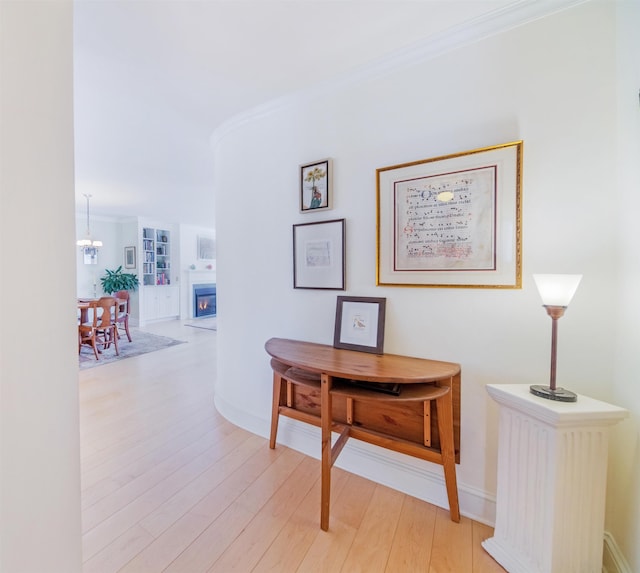 hall with crown molding, light hardwood / wood-style flooring, and a chandelier