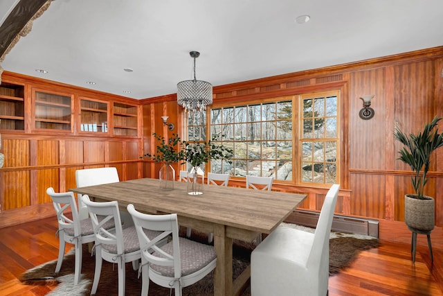 dining space featuring a baseboard heating unit, hardwood / wood-style floors, and wooden walls