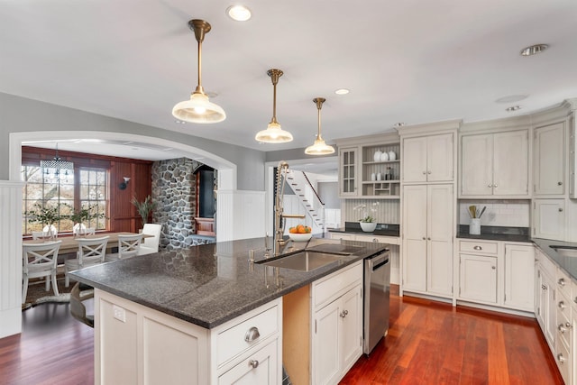 kitchen featuring tasteful backsplash, decorative light fixtures, dark hardwood / wood-style flooring, dishwasher, and a kitchen island with sink