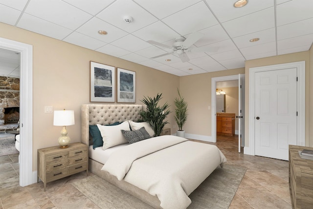 bedroom featuring ceiling fan, a drop ceiling, and a fireplace