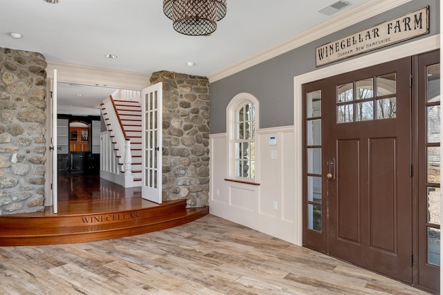 foyer entrance with ornamental molding, plenty of natural light, and light hardwood / wood-style flooring