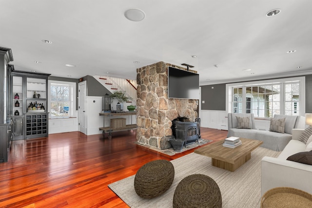 living room with dark hardwood / wood-style flooring, ornamental molding, bar, and a wood stove