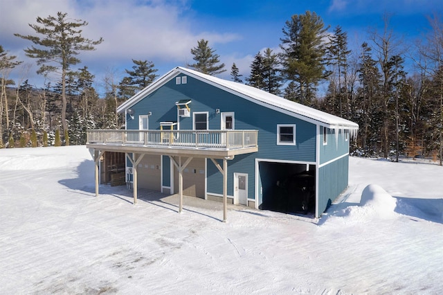 snow covered back of property with a wooden deck