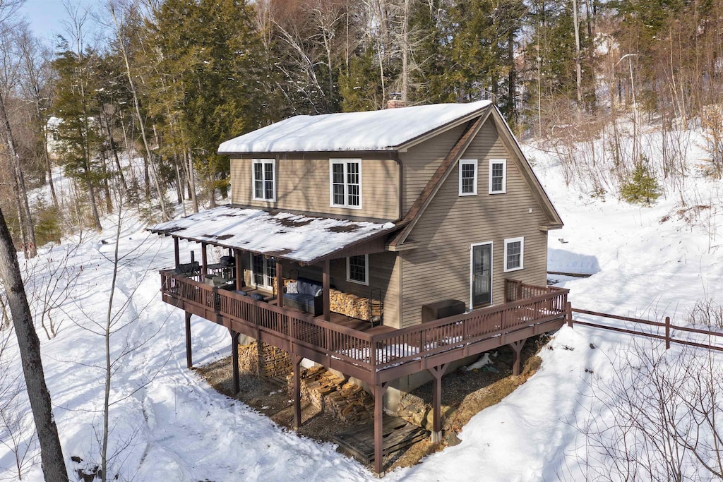 snow covered rear of property featuring a wooden deck