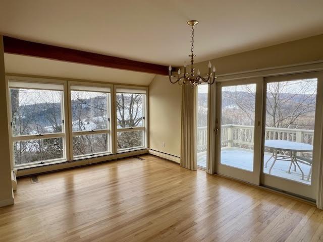 unfurnished dining area with lofted ceiling with beams, a baseboard radiator, a chandelier, and light hardwood / wood-style flooring