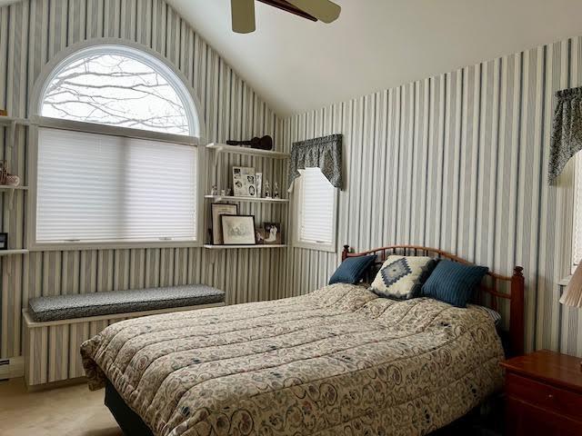 bedroom with vaulted ceiling, ceiling fan, and carpet