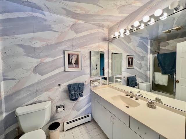 bathroom with tile patterned floors, toilet, lofted ceiling, a baseboard radiator, and vanity