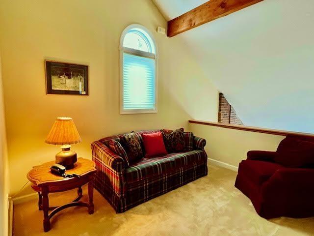 carpeted living room with vaulted ceiling with beams