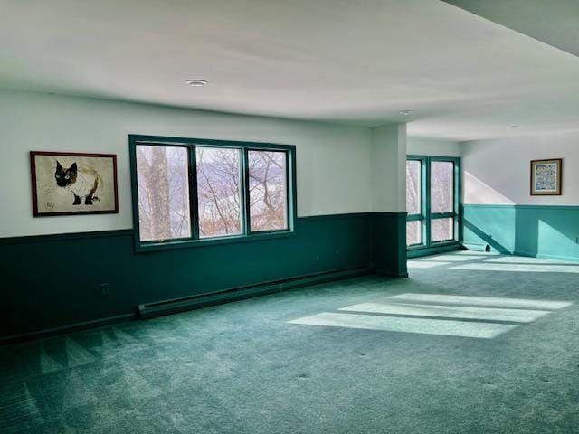 empty room featuring baseboard heating and carpet