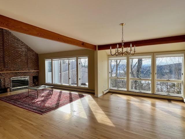 unfurnished living room featuring a brick fireplace, plenty of natural light, and light hardwood / wood-style flooring