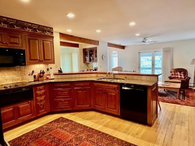 kitchen featuring sink, decorative backsplash, black appliances, and kitchen peninsula