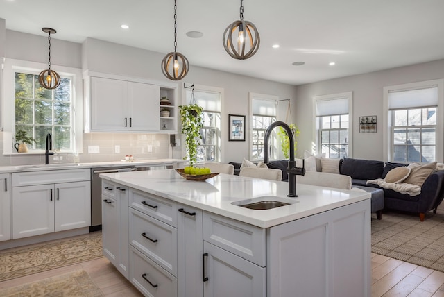 kitchen with pendant lighting, sink, an island with sink, and white cabinets