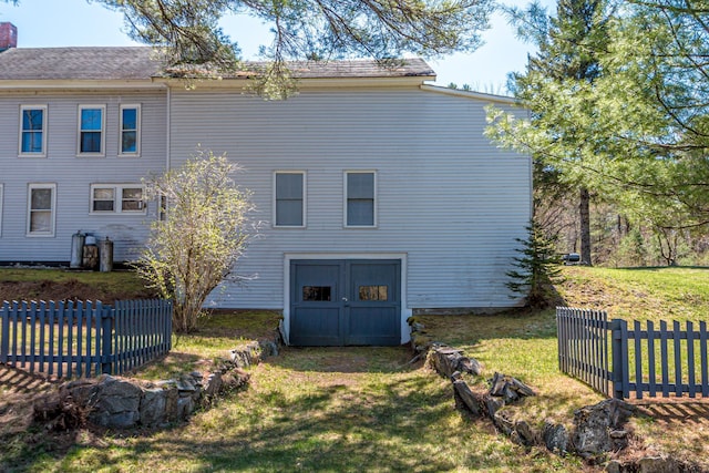 rear view of property featuring fence, a yard, and a chimney