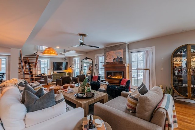 living room featuring a fireplace, ceiling fan, and light hardwood / wood-style floors