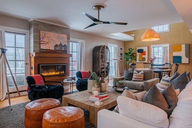 living room with a healthy amount of sunlight, wood-type flooring, a large fireplace, and ceiling fan