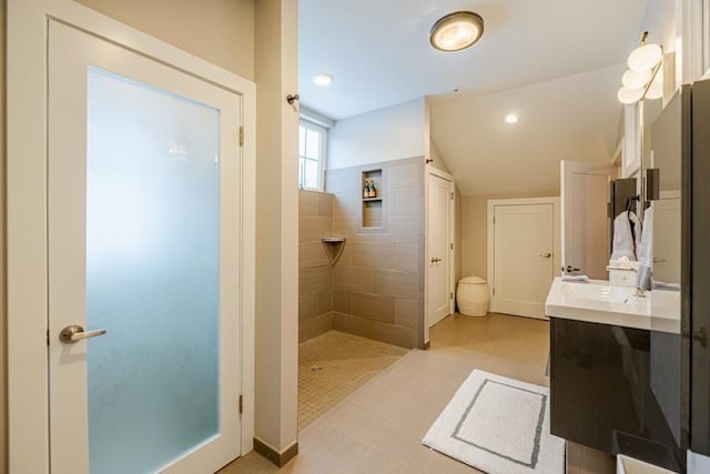 bathroom with tiled shower, vaulted ceiling, and vanity