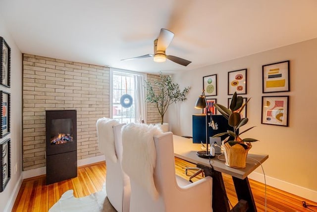 office area featuring hardwood / wood-style flooring, ceiling fan, and a brick fireplace