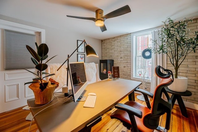 office space featuring ceiling fan, wood-type flooring, and brick wall