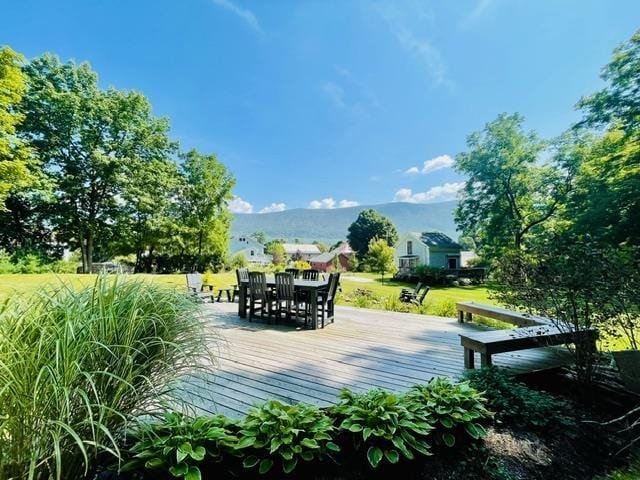 surrounding community with a deck with mountain view and a lawn