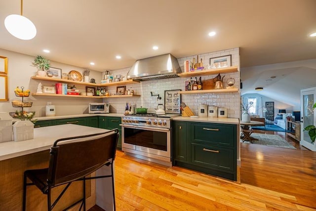 kitchen featuring light hardwood / wood-style flooring, backsplash, high end stainless steel range oven, wall chimney exhaust hood, and green cabinets