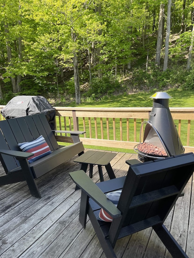 wooden deck featuring a yard and a fire pit