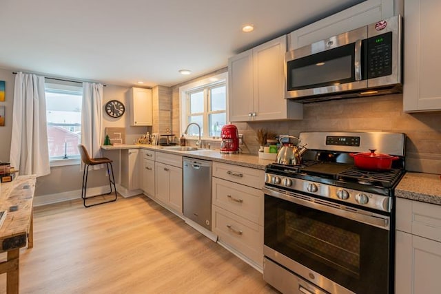 kitchen with appliances with stainless steel finishes, plenty of natural light, white cabinetry, and decorative backsplash