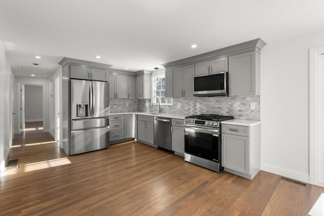 kitchen featuring sink, backsplash, dark hardwood / wood-style floors, stainless steel appliances, and gray cabinets