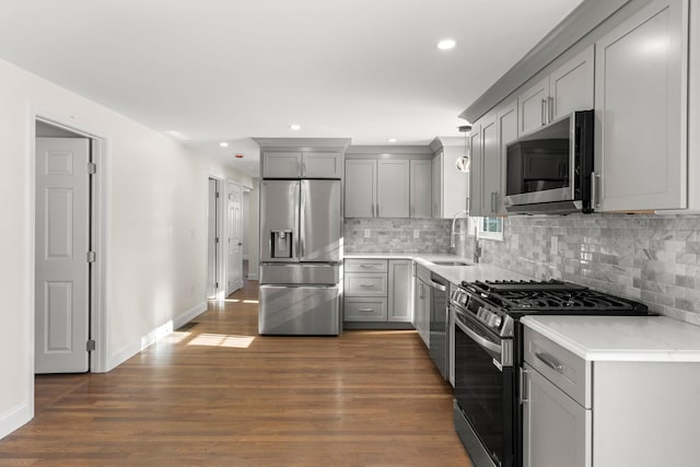 kitchen with gray cabinetry, stainless steel appliances, pendant lighting, dark hardwood / wood-style flooring, and sink