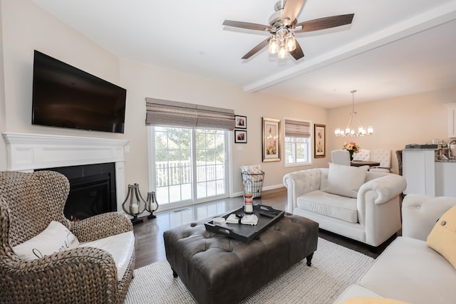 living room featuring dark wood-type flooring, beamed ceiling, and ceiling fan with notable chandelier